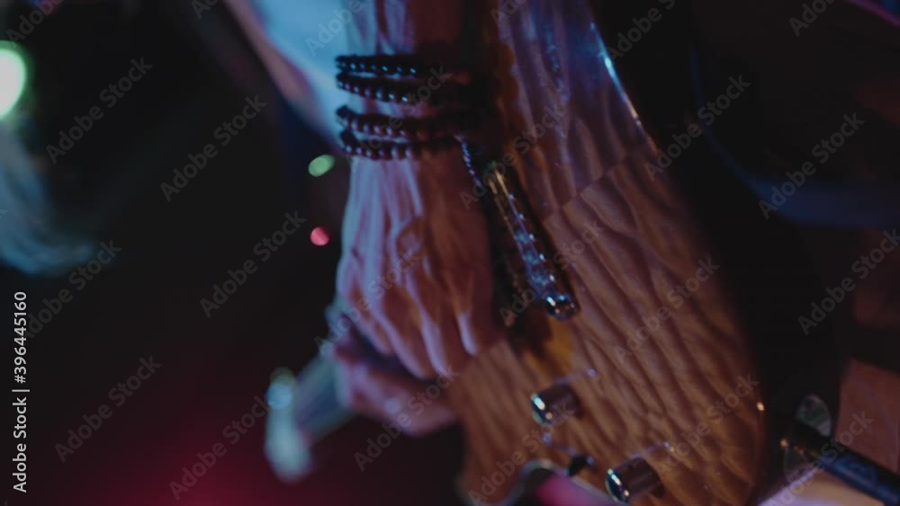 Closeup on guitarist during energetic live performance. Musician jamming, playing fast riffs in front of dancing teenagers in crowd. Rock music show in atmosphere of youth. Concept of lifestyle. Closeup on guitarist during energetic live performance. Musician jamming, playing fast riffs in front of dancing teenagers in crowd. Rock music show in atmosphere of youth. Concept of lifestyle.