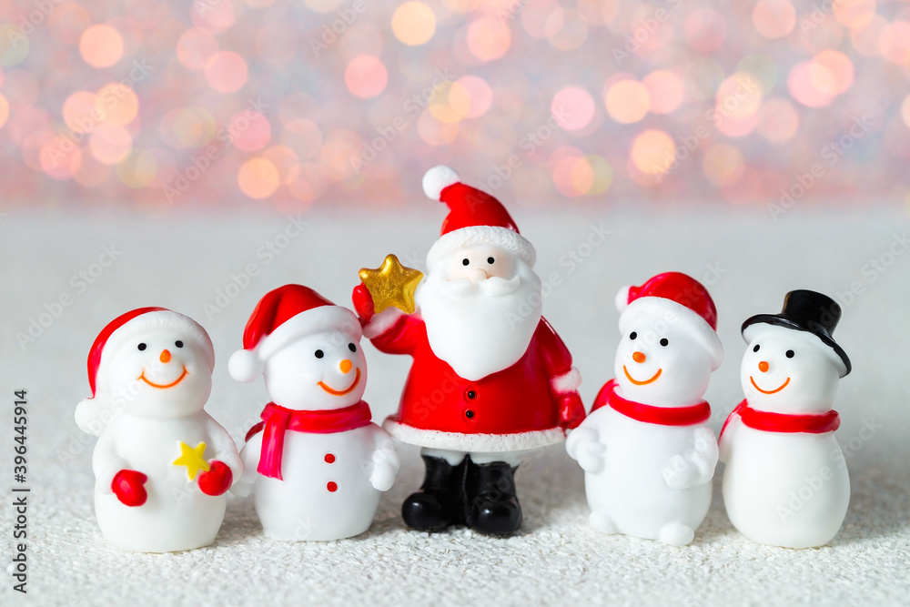 New year background with toy snowmen and Santa standing and smiling on a blurry background. Macro photography of Christmas figures. Winter holiday idea for a postcard, flyer, label, advertisement
