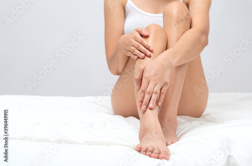 Young woman legs with slim body, smooth and soft skin against a grey background