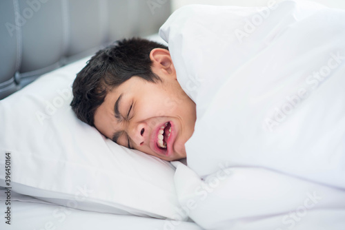 Teen boy sleeping in the bed with blanket cover happy smile face
