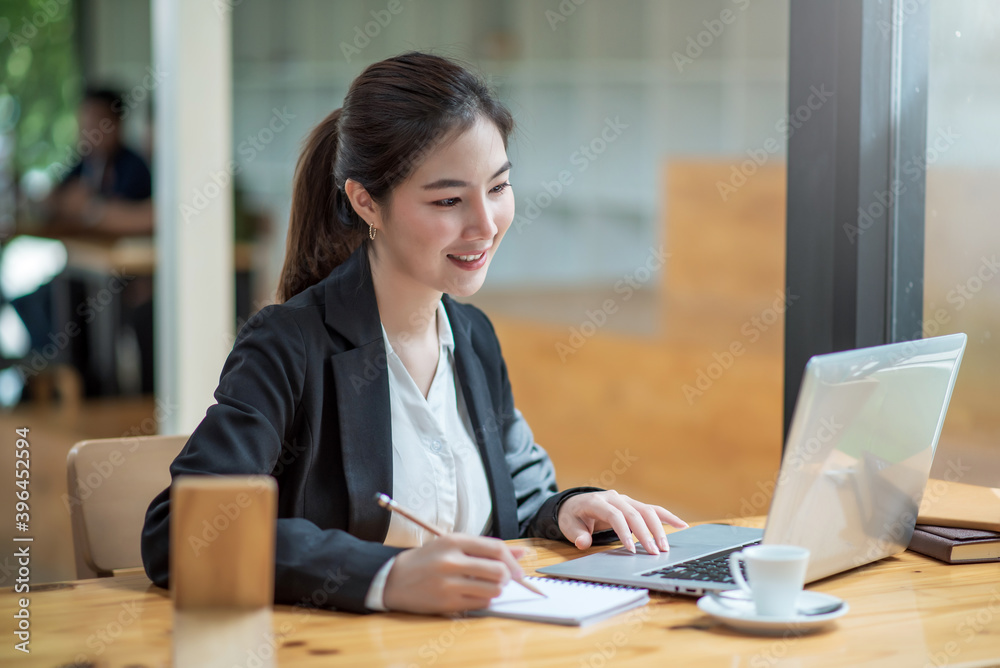 Charming asian businesswoman sitting working on laptop in office. Charming asian businesswoman sitting working on laptop in office.