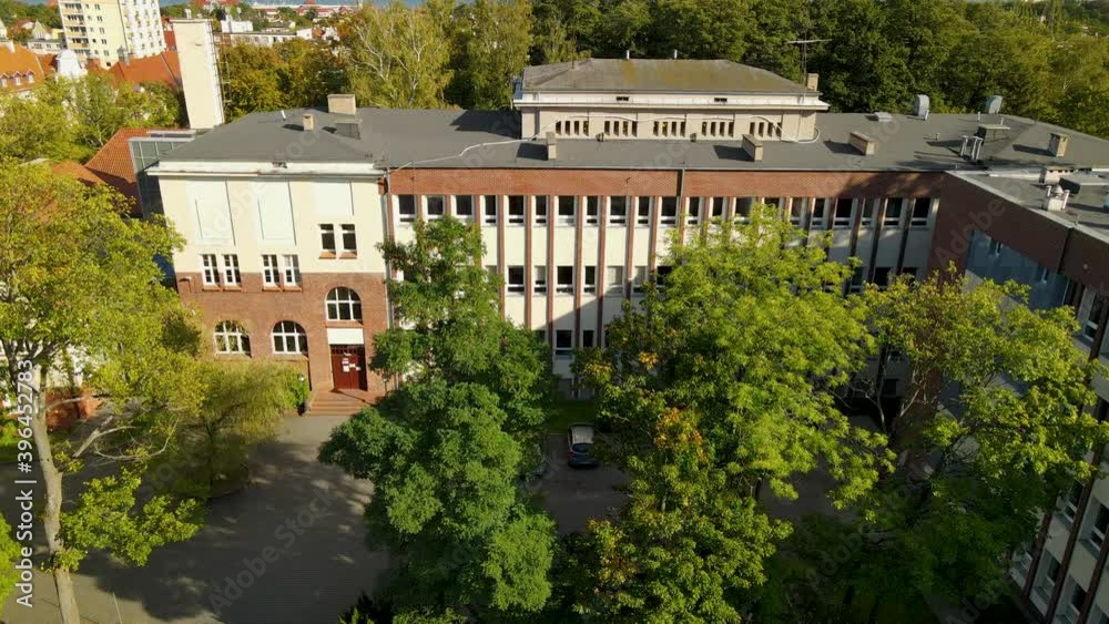 Faculty of Management University of Gdansk, old building in historical architecture from red brick and green tall tree on parking Faculty of Management University of Gdansk, old building in historical architecture from red brick and green tall tree on parking