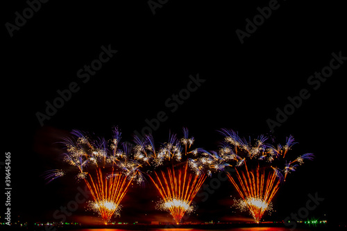 colorful fireworks,Beautiful multi color fireworks explosions lighting sky over trees silhouette and over an illuminated,celebration concept