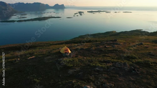 Aerial view around a tent on the Husfjell mountain, Norwegian sea background, during midnight sun, in Senja, Norway, - circling, drone shot photo