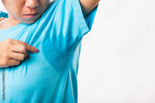 Closeup young Asian young woman hyperhidrosis sweating. Female very badly have armpit sweat stain on her clothes, studio shot isolated on white background, Healthcare medical concept