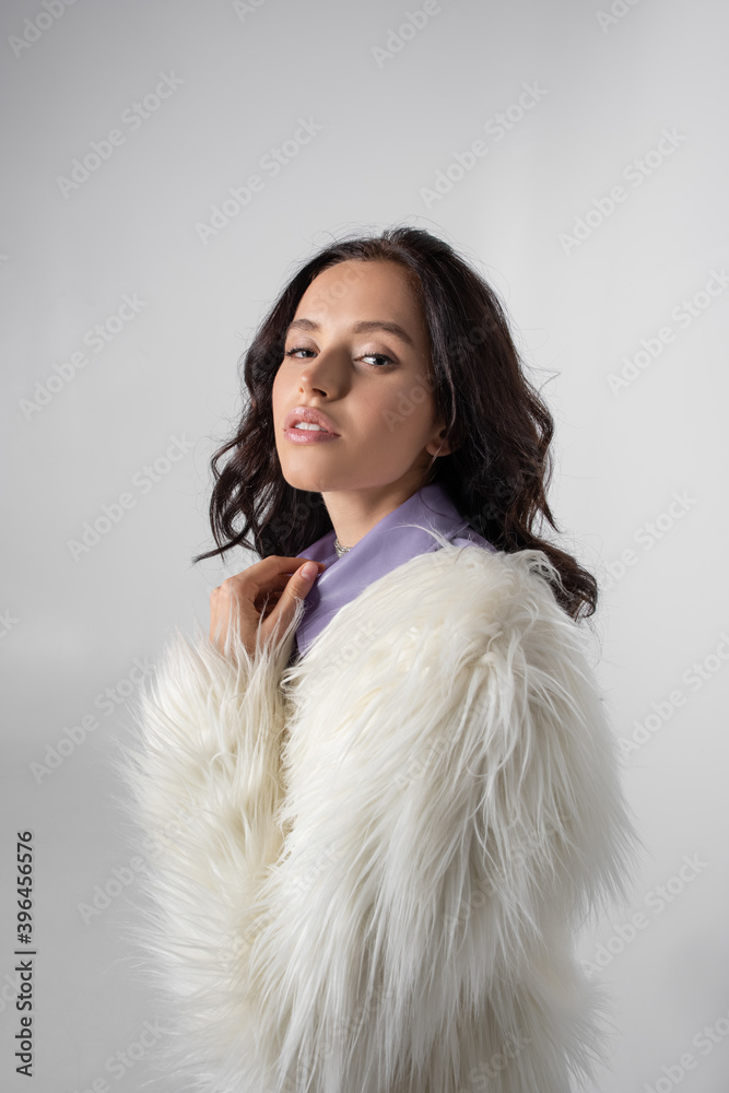 young woman in stylish white faux fur jacket posing on grey background young woman in stylish white faux fur jacket posing on grey background
