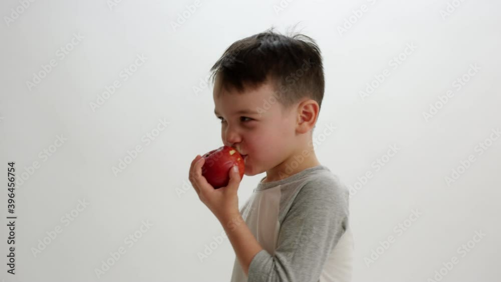 Toddler boy takes little bites of apple before turning to walk away from camera Toddler boy takes little bites of apple before turning to walk away from camera