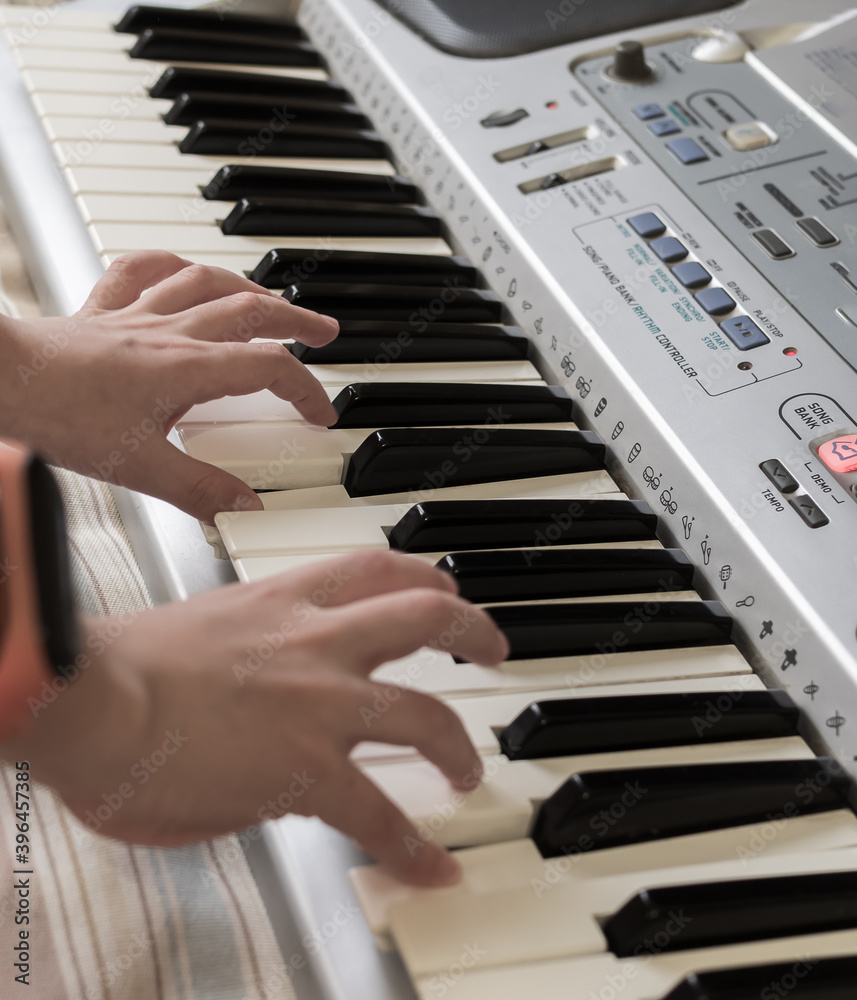 The hands of caucasian unrecognizable boy are learning to play synthesizer. A home scool. The hands of caucasian unrecognizable boy are learning to play synthesizer. A home scool.