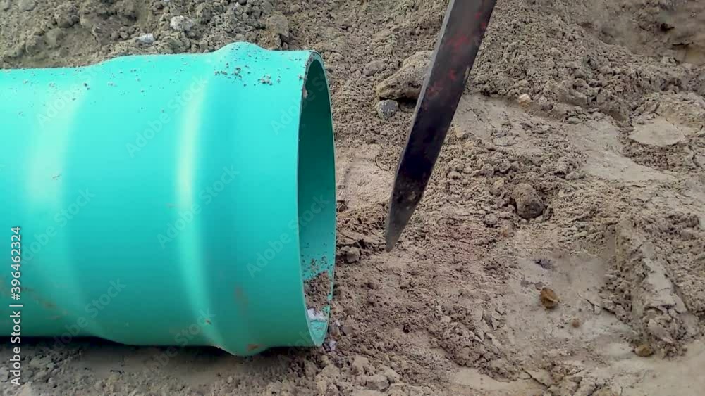 A construction worker drives a spike into the ground in preparation for assembling gravity sewer pipe on a construction site. Slow Motion. A construction worker drives a spike into the ground in preparation for assembling gravity sewer pipe on a construction site. Slow Motion.