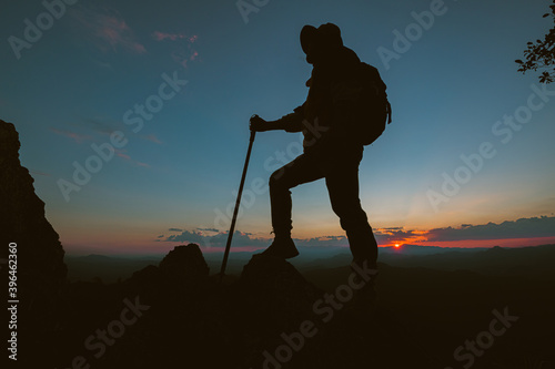 Silhouette of a man climbing a high cliff Climbers climb to the top enjoy the view A man watching the valley sunset in the evening