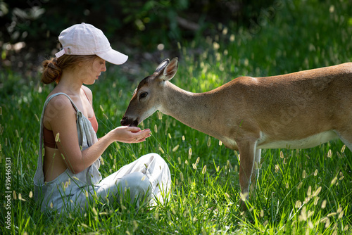 Photography Young woman feed deers bambi. Cute wild animals concept.
