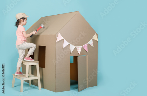 Asian little child girl building her cardboard house isolated on blue long banner with copy space for your text, Creative at home with family concept photo