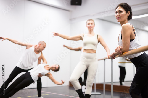 Asian girl in leotard training in ballet class with other dancers