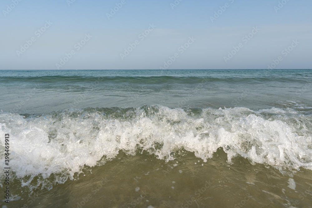 Crashing white waves and blue water and sky from the ocean or sea in the tropical warm holiday climate.