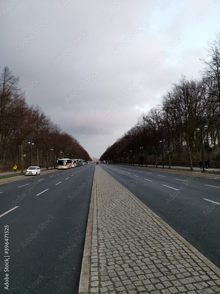 Fototapeta premium Long empty road in the winter to the brandenburger gate in berlin with parking tourist buses