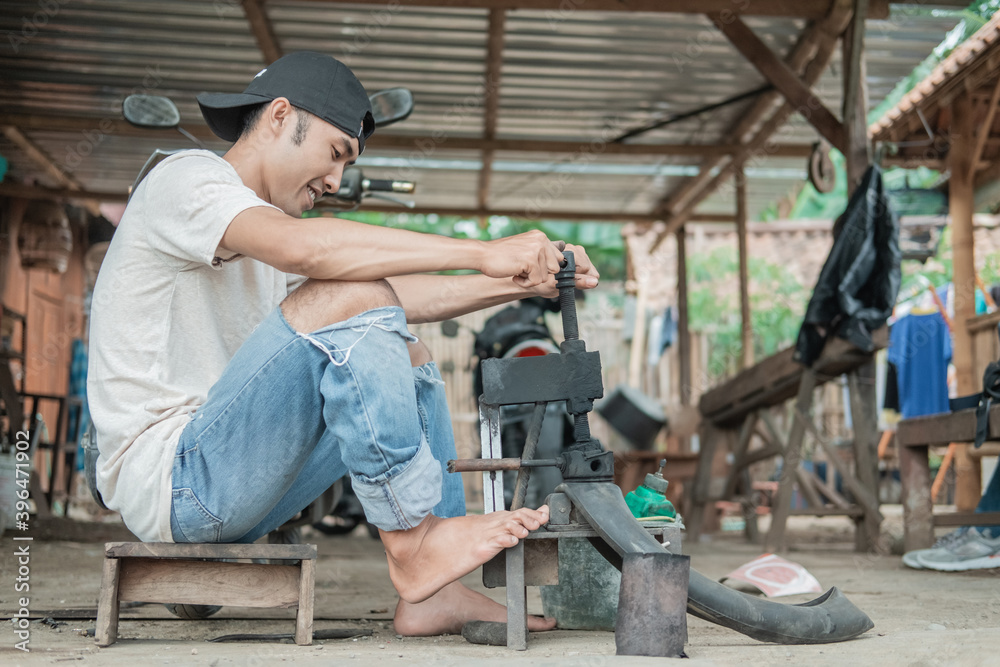 tire repairman holds the traditional press with its feet while patching tires in the repair shop