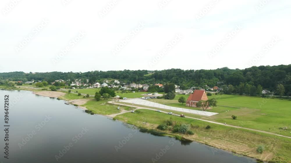 Aerial drone shot, flying over the river to small town in the distance with forest in the background