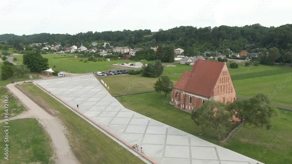 Aerial drone view flying over to red brick building and forest in the background