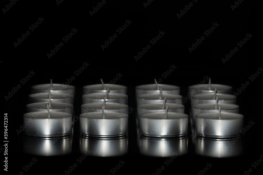 Selective focus of an arrangement of tea light candles on a dark background. Abstract concept.