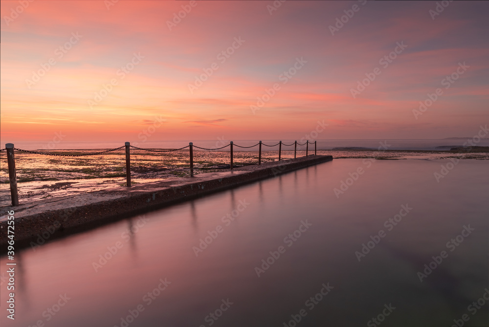 Rock pool during the calm and colourful sunrise on the coast.