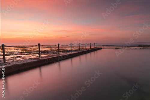 Rock pool during the calm and colourful sunrise on the coast. © Kirill