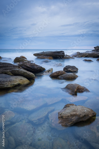 Calm pool with rocks on the coast line during cloudy and calm morning.