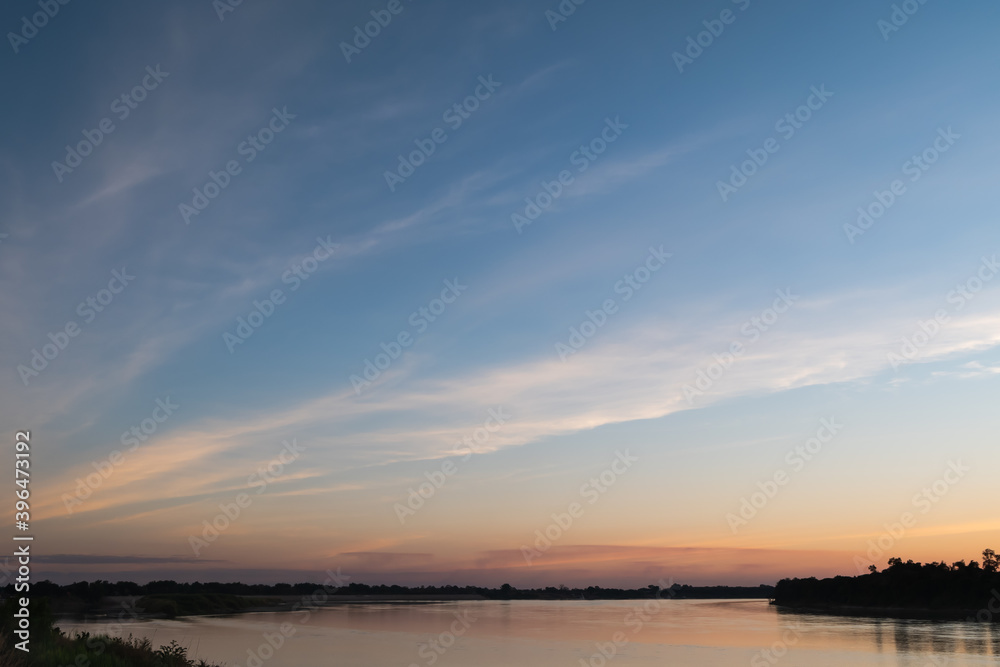 Sunset sky with Cirrus fibratus clouds over Mekong riverbank.