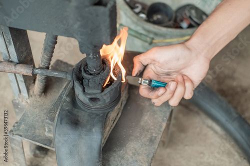 close up of tire repairman's hand when starting a fire with a lighter on a traditional press when patching a motorcycle tire