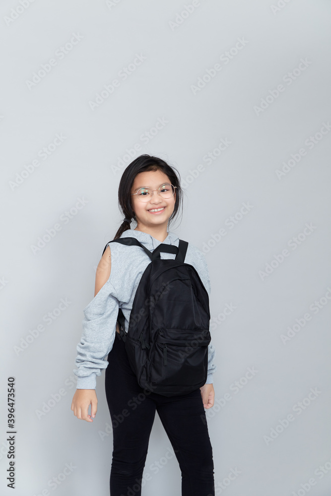 Asian little girl with backpack on grey background Asian little girl with backpack on grey background
