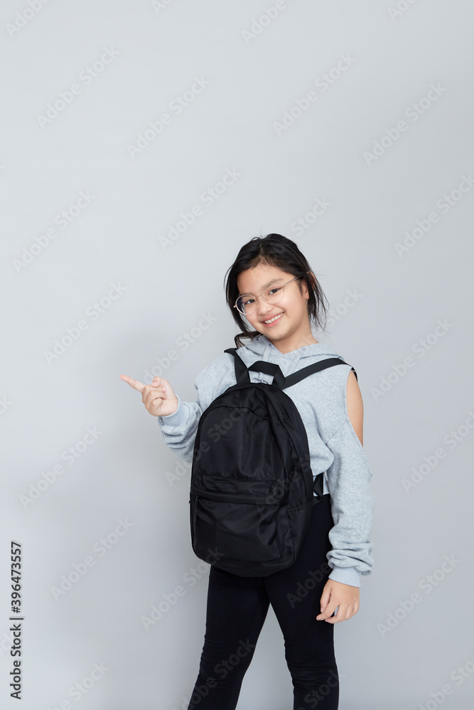 Asian little girl with backpack on grey background Asian little girl with backpack on grey background