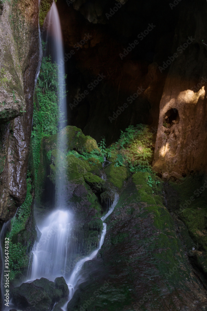 Long exposure of a water fall with rocks and green foliage