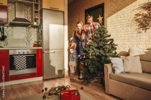 Happy family decorating a Christmas tree with boubles in the living-room. photo