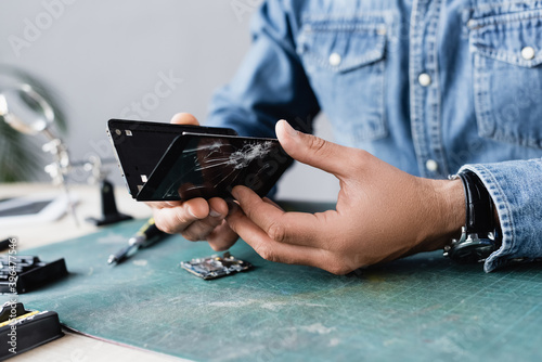 Foto Close up view of disassembled parts of broken smartphone in hands of repairman a