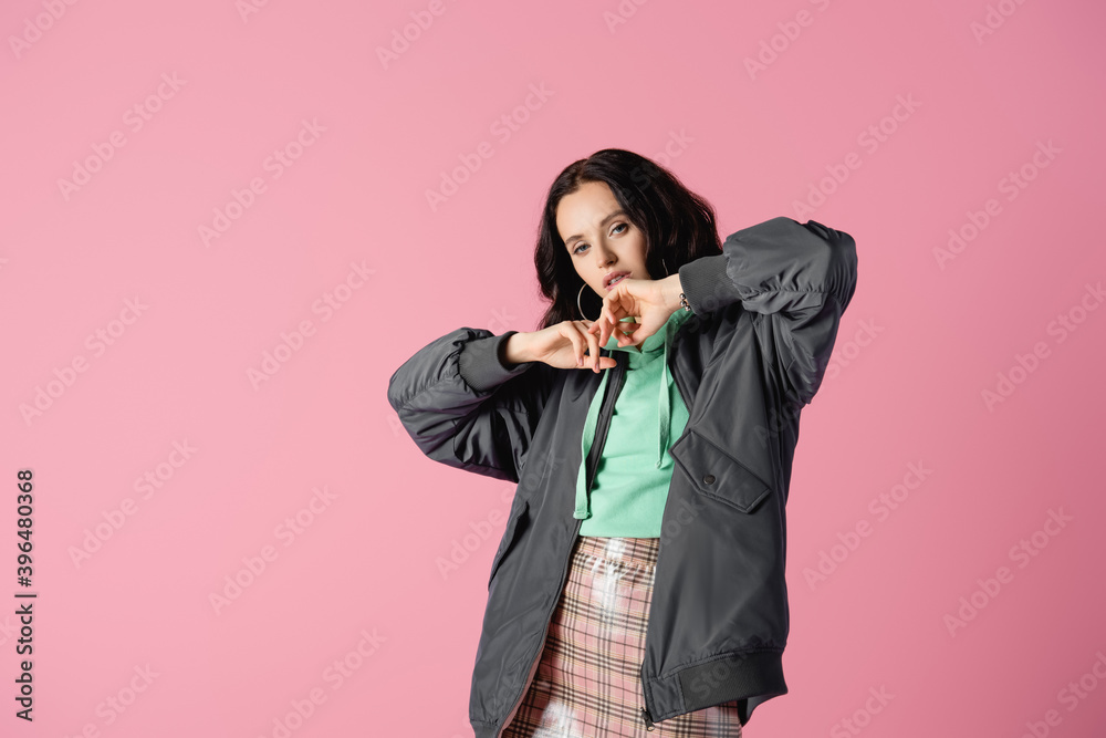  brunette young woman in casual winter outfit posing on pink background