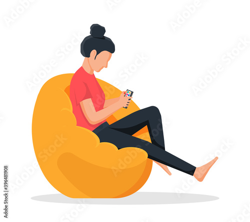 Girl sitting on bean bag chair. Woman holds smartphone in her hand. Casual female character chilling and browsing social media on mobile device. Cartoon flat vector illustration