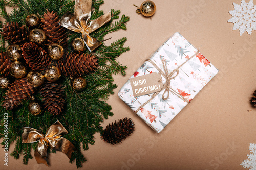 Christmas decorations flat layout with fir branches, snowflakes, golden balls, pine cones and gift box on the cardboard background. Gift with empty tag.