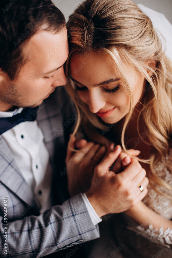 Fototapeta premium Newlyweds gently cuddle together and hold hands