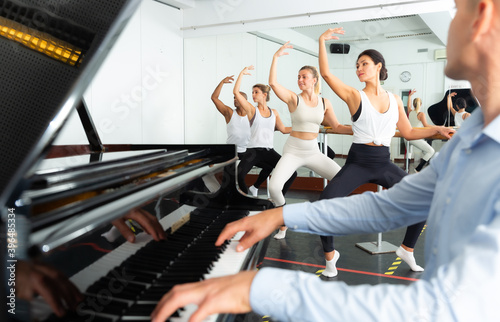 Group of people performing second position plie in the dance hall photo