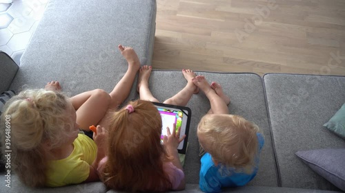 Three little friends kids using digital tablet together. Camera movement