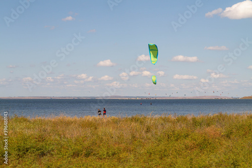 Kite parachutes are visible over the lake, a plain with orange grass.