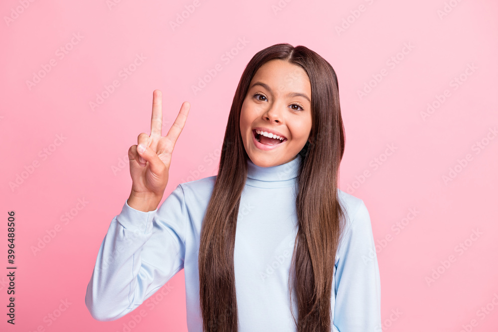 Close-up portrait of attractive glad cheerful girl showing v-sign having fun isolated over pink pastel color background Close-up portrait of attractive glad cheerful girl showing v-sign having fun isolated over pink pastel color background