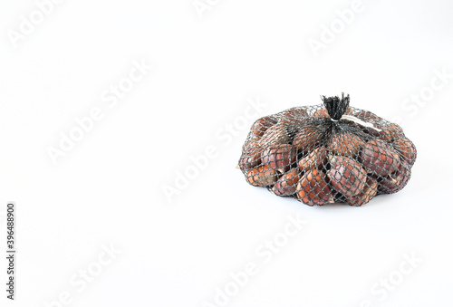 Fresh raw sweet chestnuts(Castanea sativa) in nylon net weight 1 kg on a white background with spack for text. Delicious tasty ,can be eaten raw, roasted, ground into flour, or mixed into pastries photo