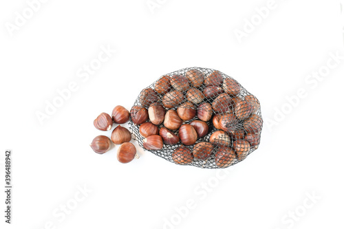 Fresh raw sweet chestnuts(Castanea sativa) in nylon net weight 1 kg on a white background with spack for text. Delicious tasty ,can be eaten raw, roasted, ground into flour, or mixed into pastries photo