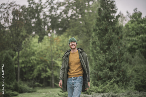 Young man in a green coat walking in the park