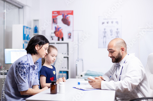 Doctor talking about diagnositc and treatment with mother of child in hospital office. Healthcare physician specialist in medicine providing health care services treatment examination.