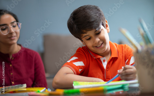 Mother looking at her son doing coloring in the notebook	 photo