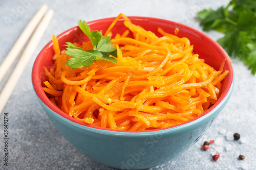 Raw grated spicy carrot salad in bowl. Korean carrot with spices and sauce.