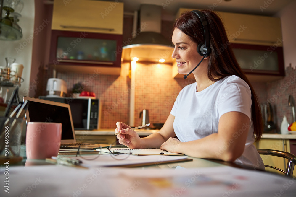 Nice person talking through a headset and writing the results Nice person talking through a headset and writing the results