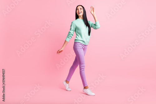 Full length photo of friendly cute young woman dressed turquoise sweater waving arm isolated pink color background