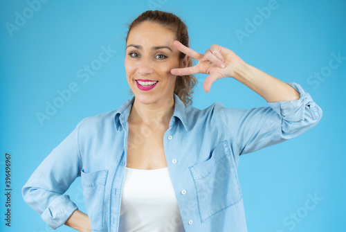 Young caucasian woman isolated showing victory sign and smiling over blue background.